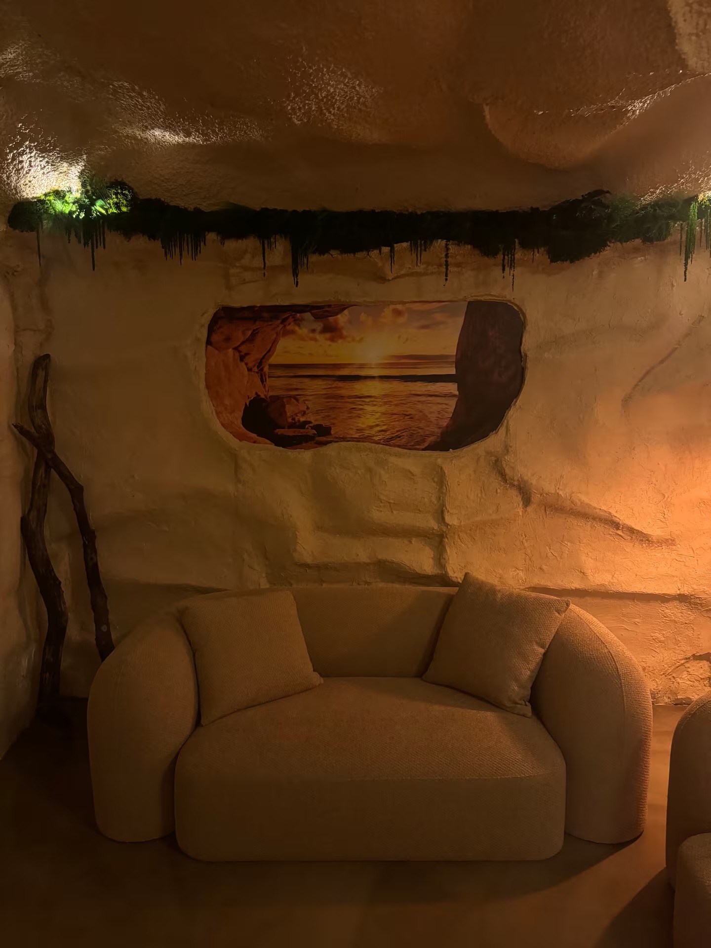 Fauteuil bouclette du salon face à une fenêtre creusée montrant un coucher de soleil
