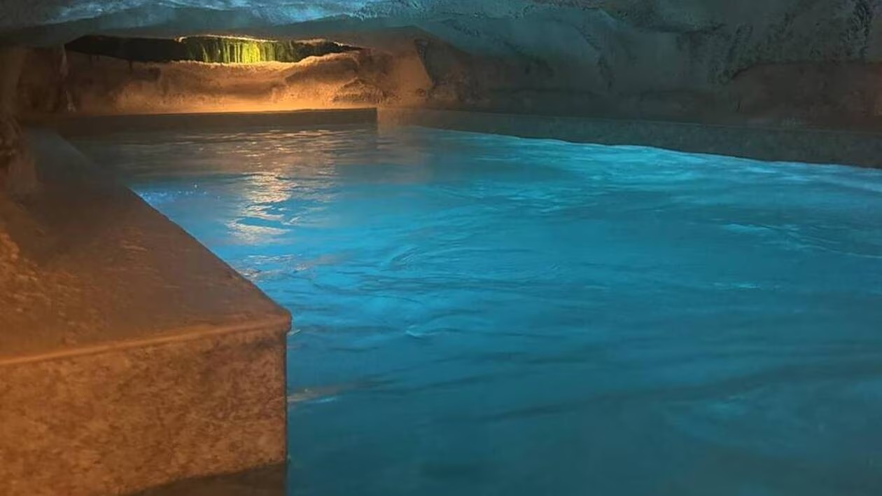 Margelle de pierre et eau turquoise de la piscine creusée dans la roche