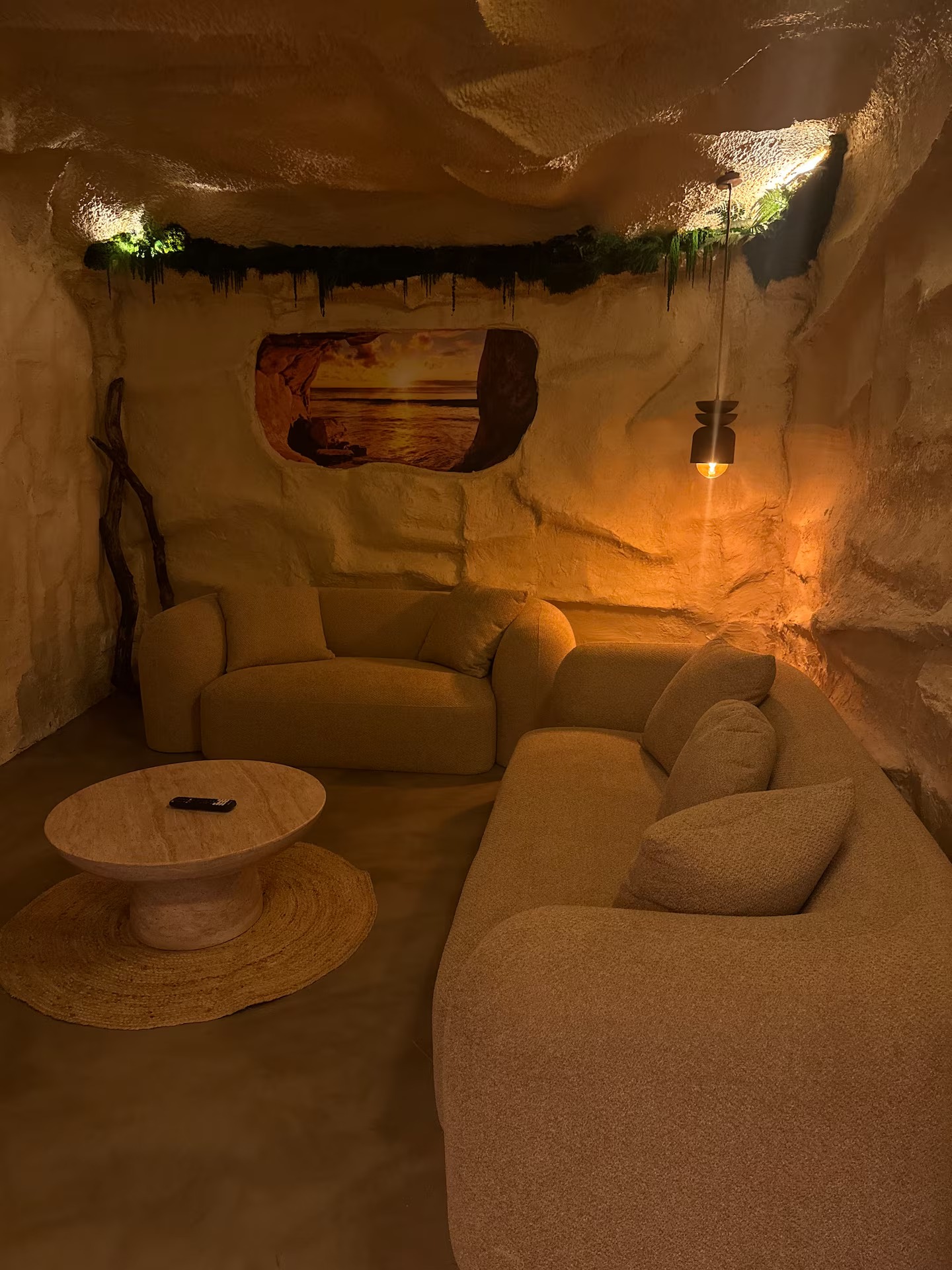 Salon troglodyte : canapés bouclette, table basse en travertin et niche lumineuse
