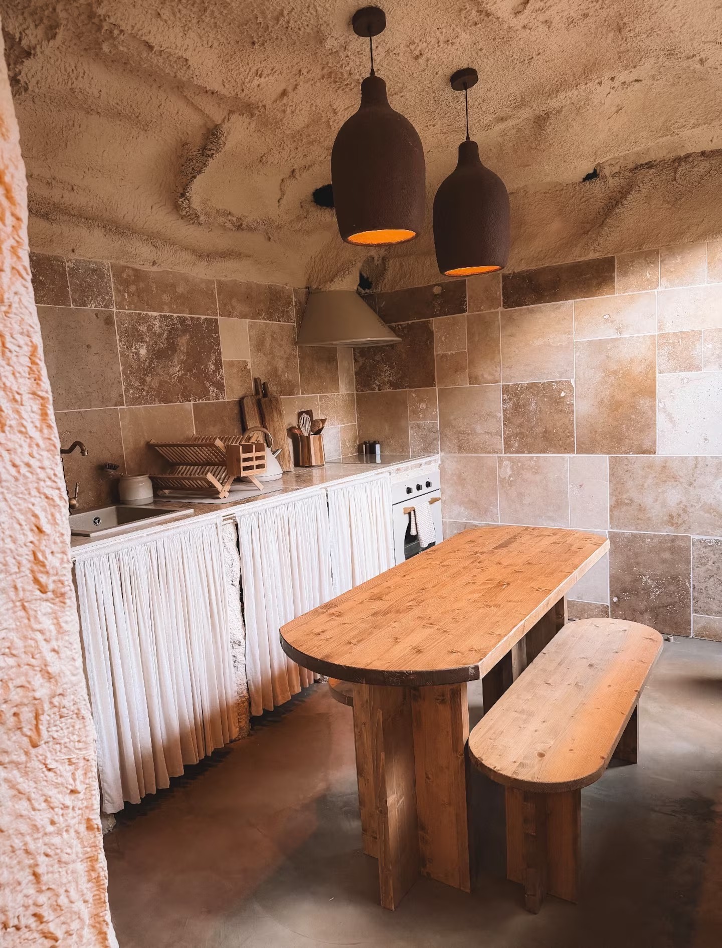 Cuisine équipée et grande table en bois sous la voûte de pierre